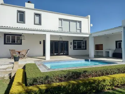 a white house with a swimming pool in front of it at Spacious Modern Home, Paarl Winelands in Paarl