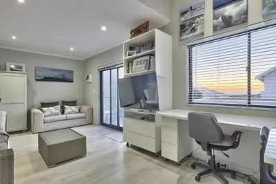 a living room with a desk and a television at Luxury Mini Villa Sunset Beach Cape Town in Cape Town
