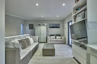 a living room with a couch and a table at Luxury Mini Villa Sunset Beach Cape Town in Cape Town
