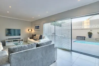 a living room with a couch and a swimming pool at Luxury Mini Villa Sunset Beach Cape Town in Cape Town