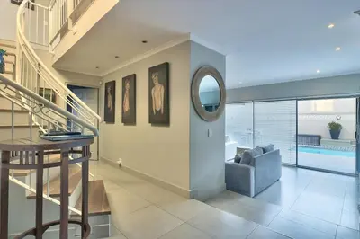 a living room with a staircase and a mirror at Luxury Mini Villa Sunset Beach Cape Town in Cape Town