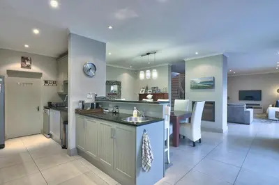 a kitchen and living room with a sink and a table at Luxury Mini Villa Sunset Beach Cape Town in Cape Town