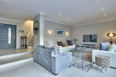 a living room with a couch and a tv at Luxury Mini Villa Sunset Beach Cape Town in Cape Town
