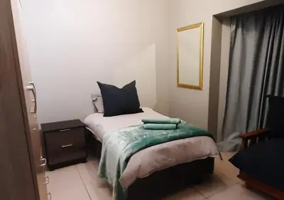 a bedroom with a bed with a green blanket on it at Apartment in Flamingo Vlei in Cape Town