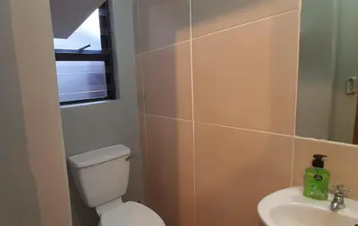 a bathroom with a white toilet and a sink at Apartment in Flamingo Vlei in Cape Town