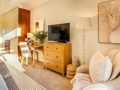 a living room with a television on a dresser with a desk at 74 on Marine in Hermanus