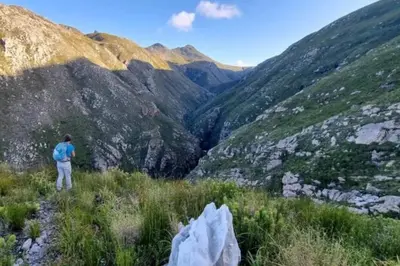 a man standing on a mountain looking at a valley at Silvertree Collective Ocean and Mountain View in Bettyʼs Bay