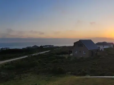 a house on a hill with the ocean in the background at Silvertree Collective Ocean and Mountain View in Bettyʼs Bay