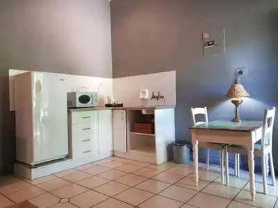 a small kitchen with a table and a refrigerator at Simondium's Country Lodge in Simondium