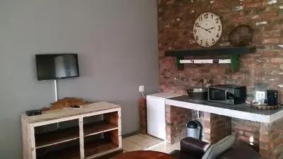 a living room with a clock on a brick wall at Simondium's Country Lodge in Simondium
