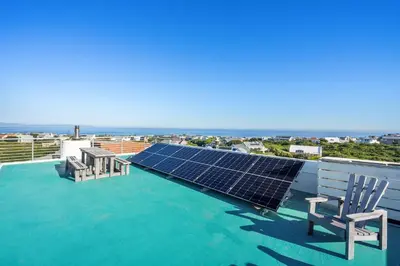 a solar array on the roof of a house with two chairs at Vermont Dreamcatcher in Hermanus