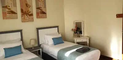 a bedroom with two beds and a mirror at self-catering in Gordonʼs Bay