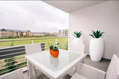 a white table and chairs on a balcony with plants at Apartments on Century in Cape Town