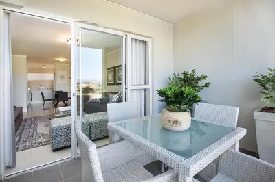 a dining room with a glass table and chairs at Apartments on Century in Cape Town