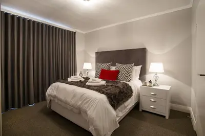 a bedroom with a large bed with red pillows at Apartments on Century in Cape Town