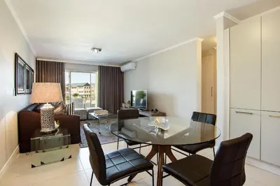 a living room with a glass table and chairs at Apartments on Century in Cape Town