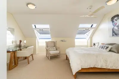 a bedroom with skylights and a bed and a desk at Dolphin Beach Penthouse in Cape Town