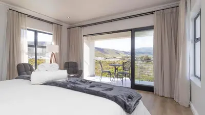 a bedroom with a large bed and a large window at Ocean Whisper Villa near Westcliff coastal paths in Hermanus