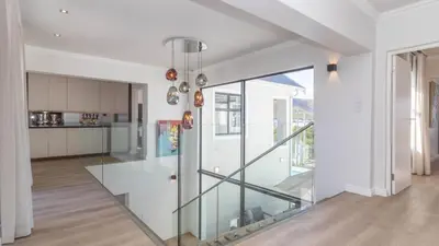 a glass staircase in a house with a kitchen at Ocean Whisper Villa near Westcliff coastal paths in Hermanus