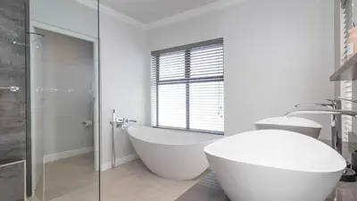 a white bathroom with a tub and a shower at Ocean Whisper Villa near Westcliff coastal paths in Hermanus