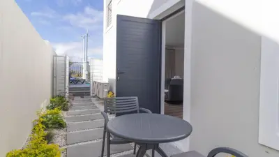a patio with a table and chairs on a balcony at Ocean Whisper Villa near Westcliff coastal paths in Hermanus