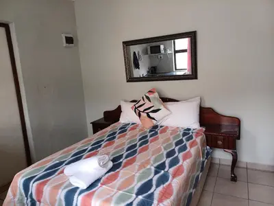 a bedroom with a bed with a mirror on the wall at Overnight Lodge in Cape Town