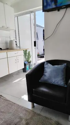 a black couch in a living room with a tv at Kenwyn Micro Cottage in Cape Town