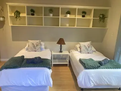 two beds in a room with shelves and plants at Cozy garden Guest Suite in charming Claremont in Cape Town