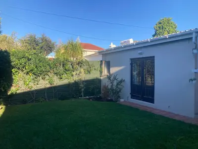 a white house with a yard with green grass at Cozy garden Guest Suite in charming Claremont in Cape Town