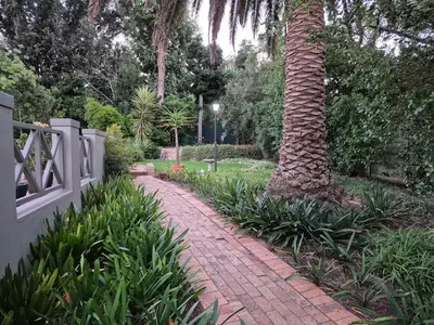 a brick path next to a palm tree next to a fence at Mistys Studio Durbanville in Durbanville
