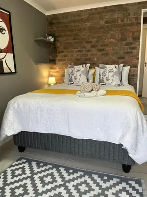 a bedroom with a large bed with a brick wall at Three on Firmount in Somerset West