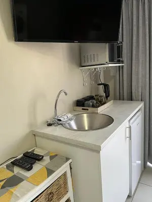 a kitchen with a sink and a microwave at Three on Firmount in Somerset West