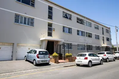three cars parked in front of a white building at Mountain View Coastal Retreat in Strand