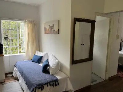 a bedroom with a bed with a mirror and a window at William's Cottage in Franschhoek