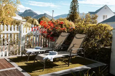two chairs sitting in a yard next to a white fence at The Crescent Hideaway in Franschhoek