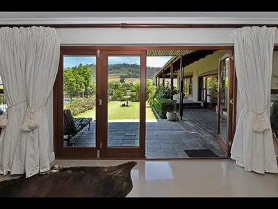 an open door to a patio with white curtains at The Manor House at Roubaix Estate in Franschhoek
