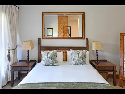 a bedroom with a large white bed with two night stands at The Manor House at Roubaix Estate in Franschhoek