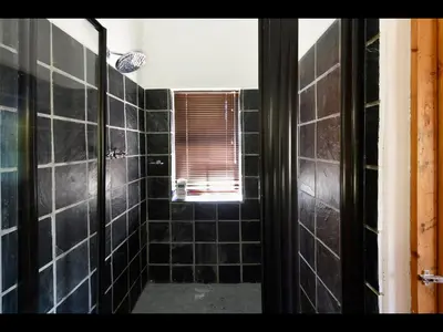 a bathroom with black tiled walls and a window at The Manor House at Roubaix Estate in Franschhoek