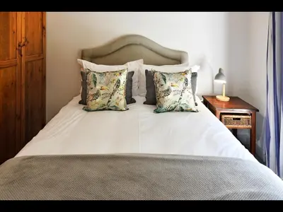 a bedroom with a white bed with pillows and a table at The Manor House at Roubaix Estate in Franschhoek