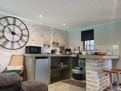 a kitchen with a large clock on a brick wall at 7th Heaven Guest Cottage in Paarl