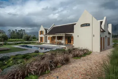 a white house with a swimming pool in front of it at Skaap huis in Sir Lowryʼs Pass