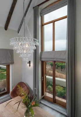 a chandelier in a dining room with windows at Skaap huis in Sir Lowryʼs Pass