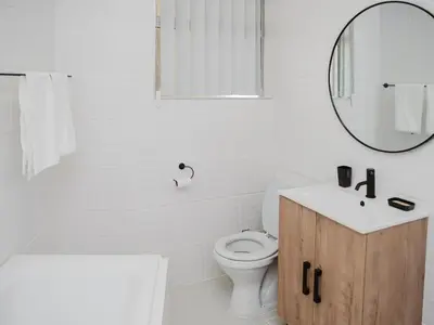 a white bathroom with a toilet and a mirror at Romilly Beachfront 92 in Strand