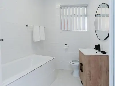 a white bathroom with a tub sink and a toilet at Romilly Beachfront 92 in Strand