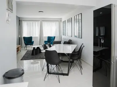 a dining room with a white table and blue chairs at Romilly Beachfront 92 in Strand