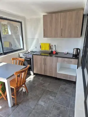 a kitchen with wooden cabinets and a table and a stove at Pine House - self-catering in Cape Town