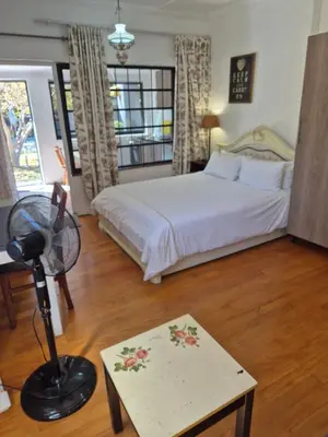 a bedroom with a bed and a desk with a fan at Pine House - self-catering in Cape Town
