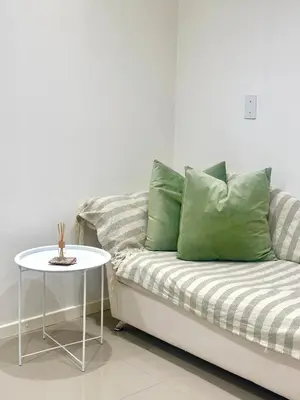 a couch with green pillows and a table at Lalla Cottages - Cape Town in Cape Town