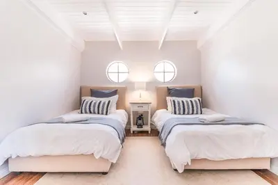 two beds in a room with two windows at Geheim Luxury Seafront in Hermanus