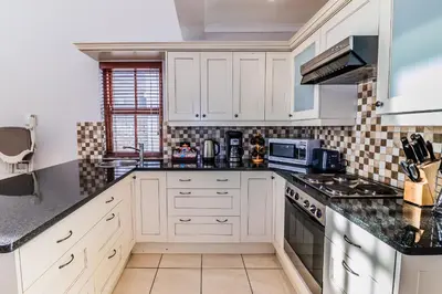 a kitchen with white cabinets and black counter tops at Geheim Luxury Seafront in Hermanus